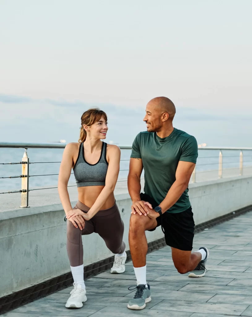 fit couple doing lunges together on a coastal prom utc